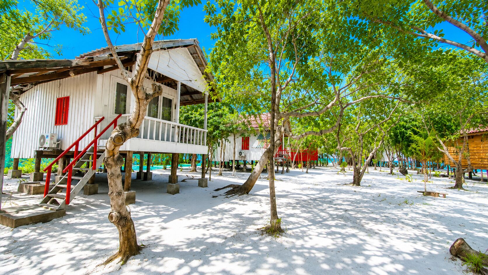 A beachside resort with wooden buildings, a staircase, and a sandy area.