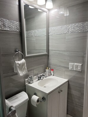 Ein modernes Badezimmer mit einem großen Spiegel, einem Waschbecken und einer Toilette.