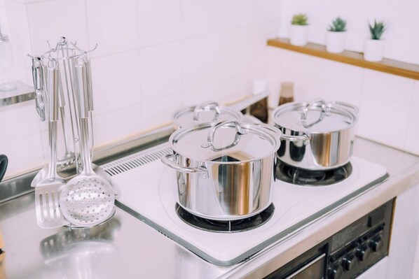 A kitchen with stainless steel pots on a stove, a colander, and a hanging utensil rack. - Osaka Castle House, Sleeps 14, Pet OK · Parking (Osaka)