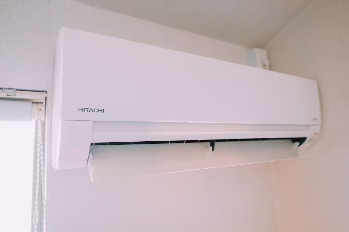 Een wit, aan de muur bevestigd airco-apparaat, merknaam 'HITACHI' is zichtbaar op de voorkant.