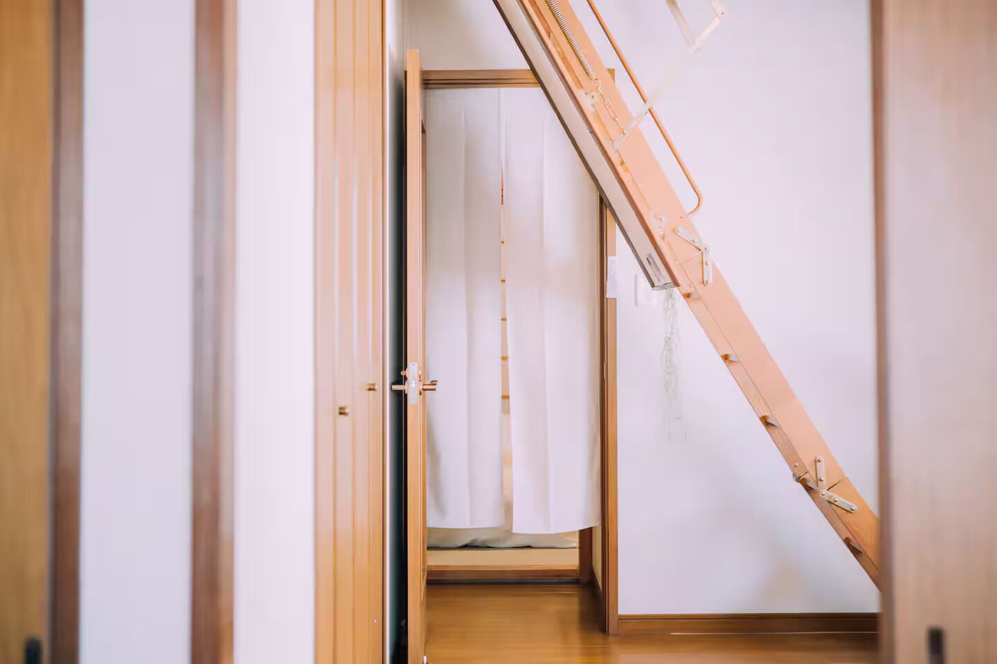 Un corridoio stretto con porte e una scala in legno.