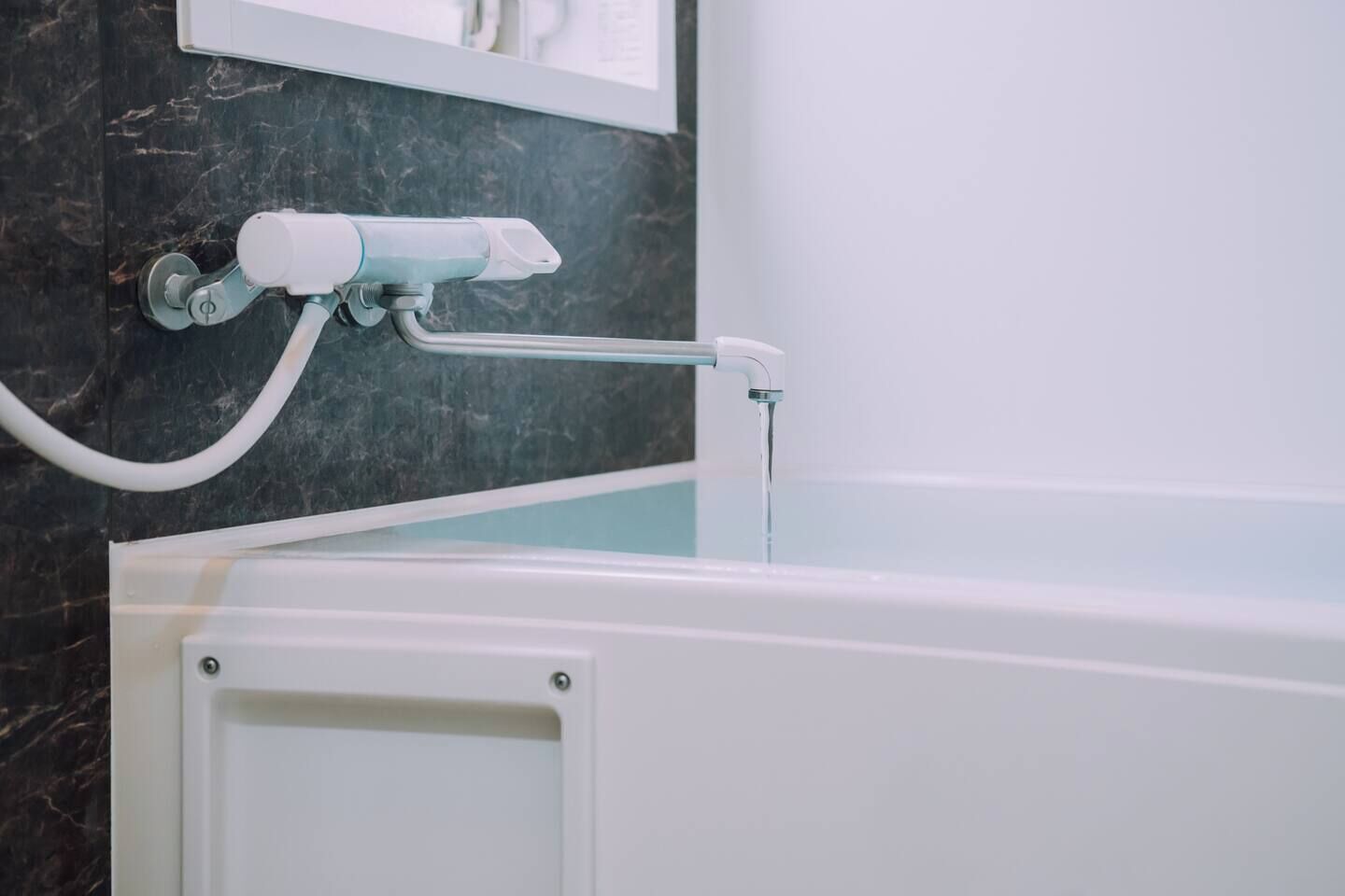 A bathroom with a bathtub, a handheld showerhead, and a towel rack.