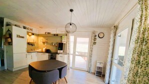 A compact kitchen with white cabinets, a black dining table, and a hanging light fixture.