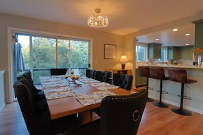 Uma sala de jantar com uma mesa de madeira grande, cadeiras estofadas pretas e um lustre.