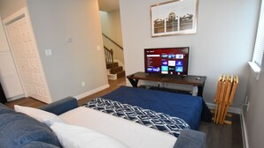 Un dormitorio con cama, televisión, escritorio y silla.