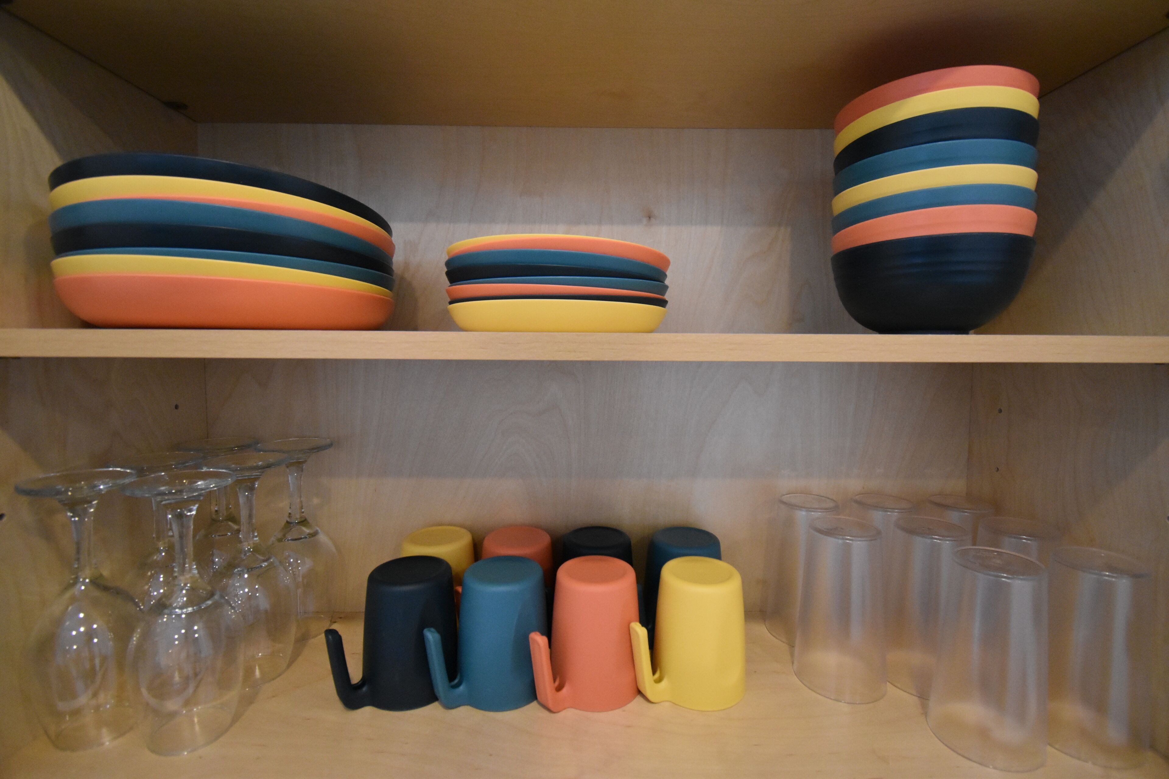 A shelf with colorful ceramic mugs and glasses.