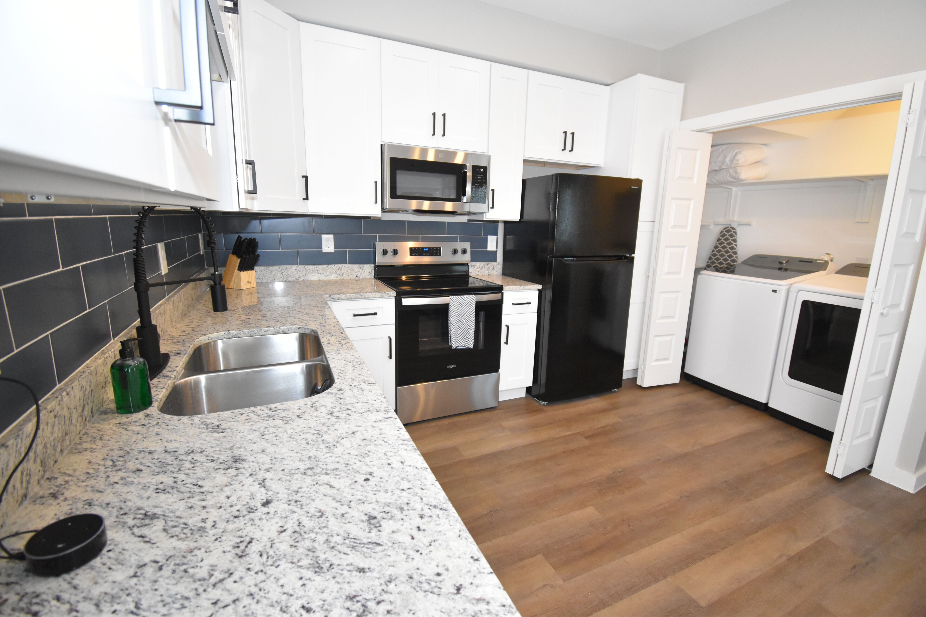 A modern kitchen with white cabinets, stainless steel appliances, and a granite countertop.