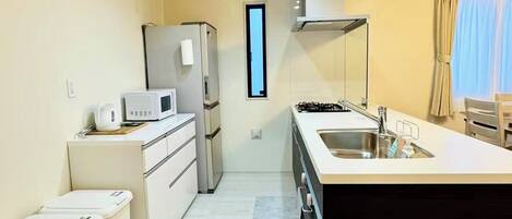 A compact kitchen with a central island, a refrigerator, a microwave, and a stove.