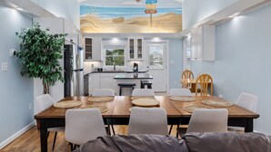 A modern kitchen with white cabinets, a wooden dining table with placemats, and a ceiling fan. - 5BR Channel Home w/ Heated Pool + Fire Pit (North Myrtle Beach)