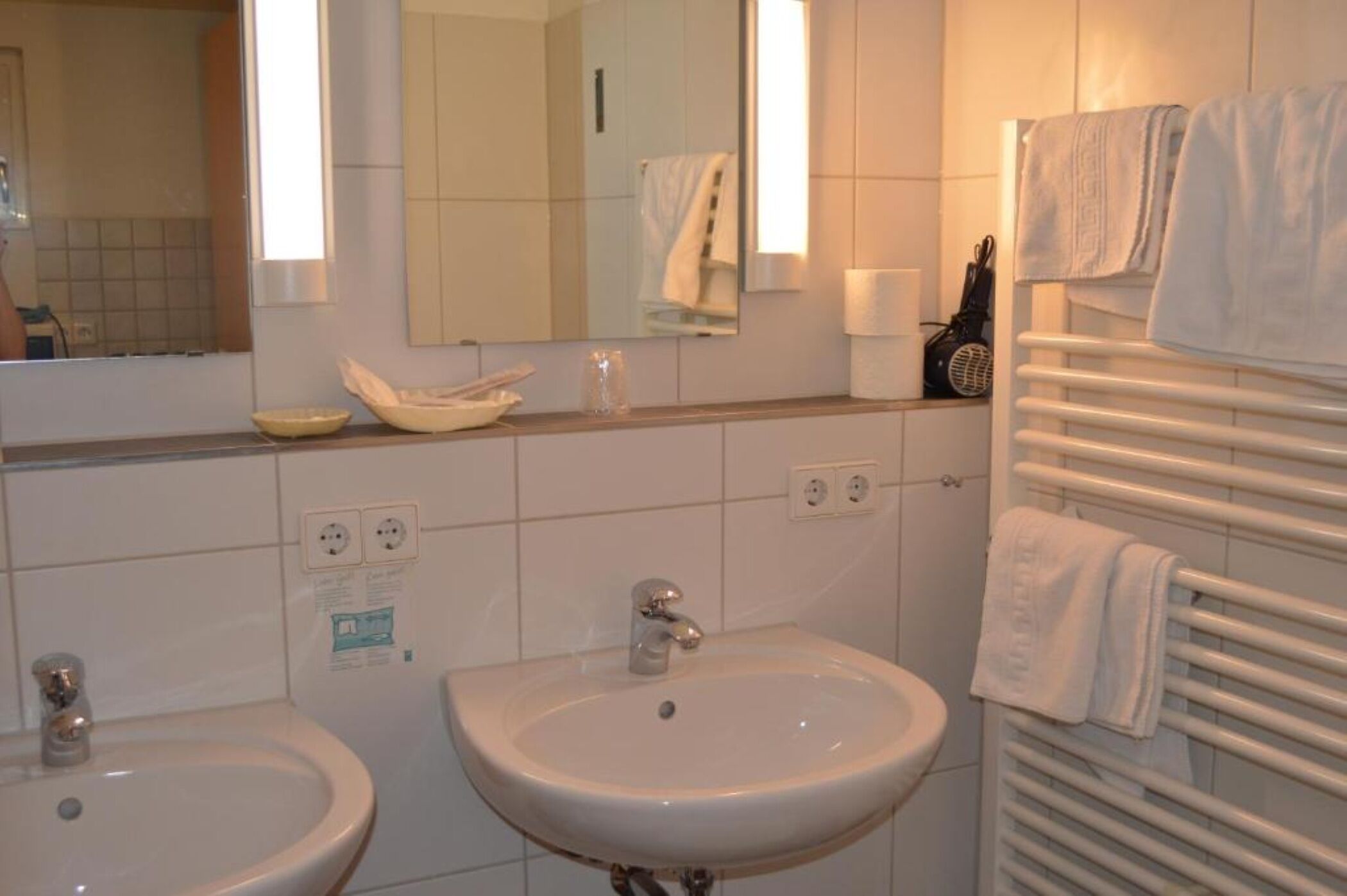 Un baño con dos lavamanos, un espejo y un toallero.