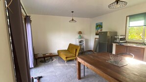 Una cocina amplia con una mesa de comedor, un sillón amarillo y un refrigerador.