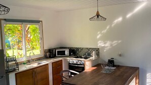 Una cocina con una mesa de madera, armarios y ventana con vistas a un jardín.