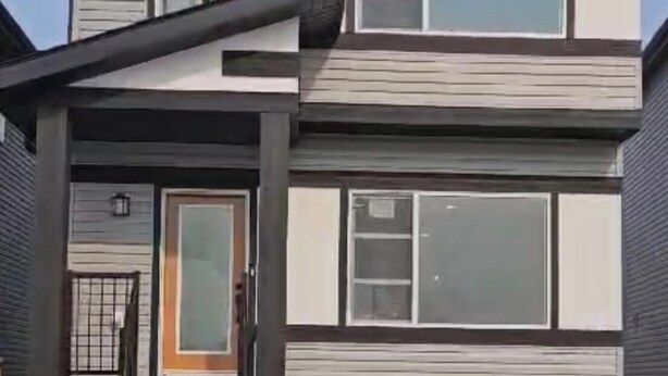 Ein modernes, zweistöckiges Haus mit markantem Satteldach, großen Fenstern und einer Haustür mit einer kleinen Veranda.