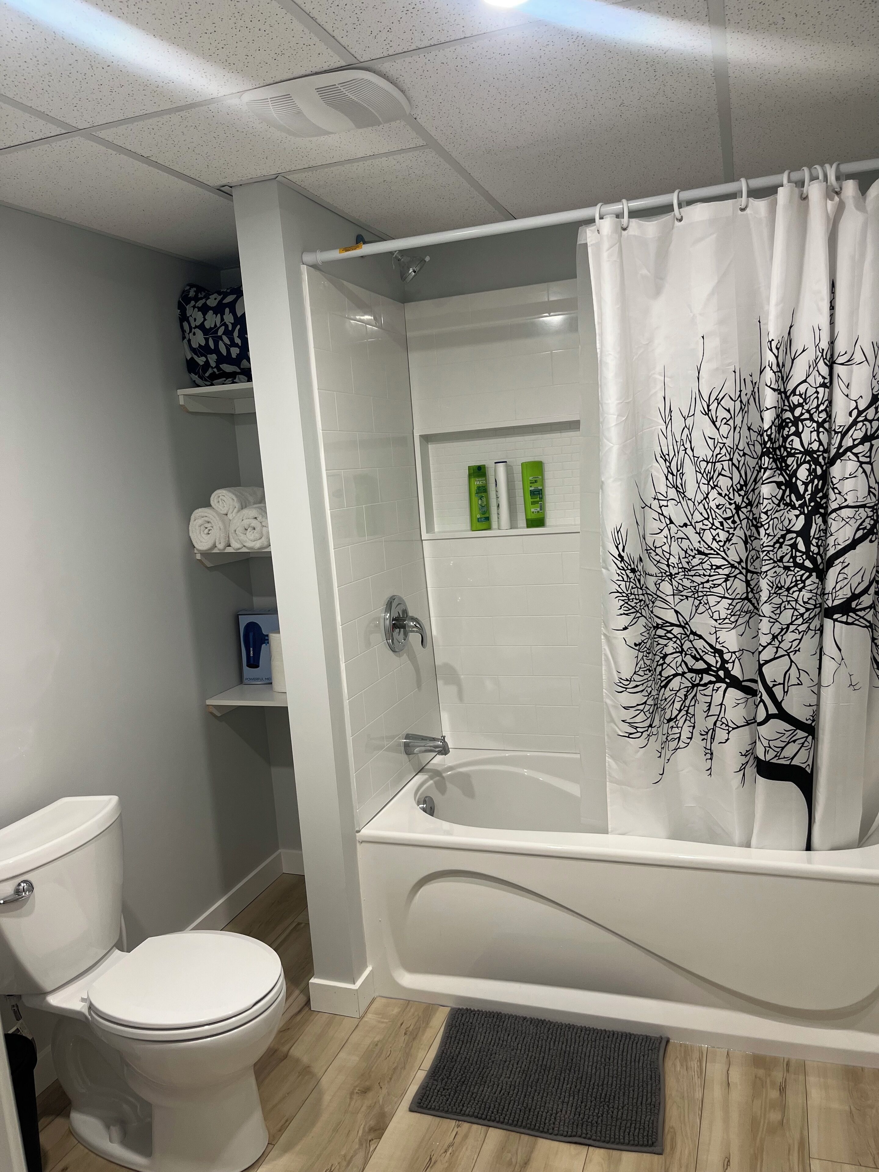 A modern bathroom with a white bathtub, toilet, and shower area.