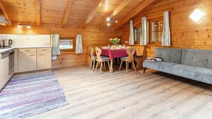 Et hyggeligt interiør i en hytte med spiseplads, en sofa og et køkken.