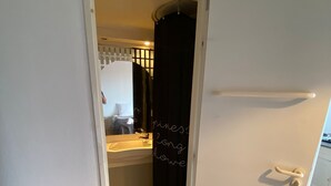 Een kleine badkamer met douchegordijn, wastafel en spiegel.