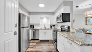 A modern kitchen with white cabinetry, stainless steel appliances, and a granite countertop.