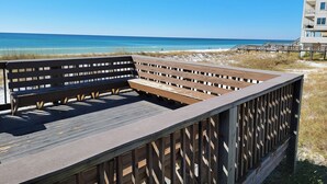 A wooden deck with benches overlooking a beach and ocean.