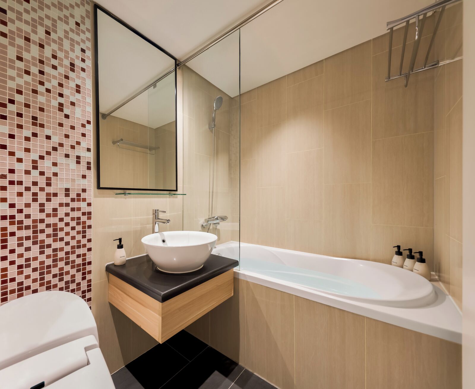 A modern bathroom with a white sink, a glass-enclosed shower, and a beige tiled wall.