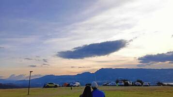 A couple flying a kite in a grassy field with mountains in the background.