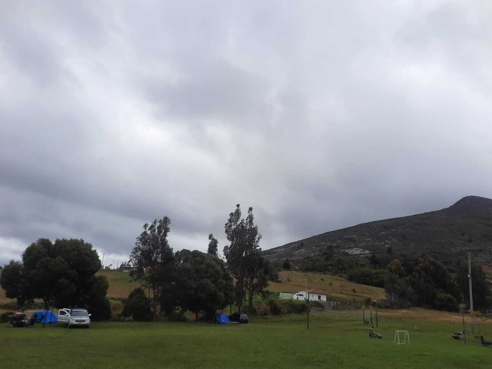 A grassy field with tents and a white building.