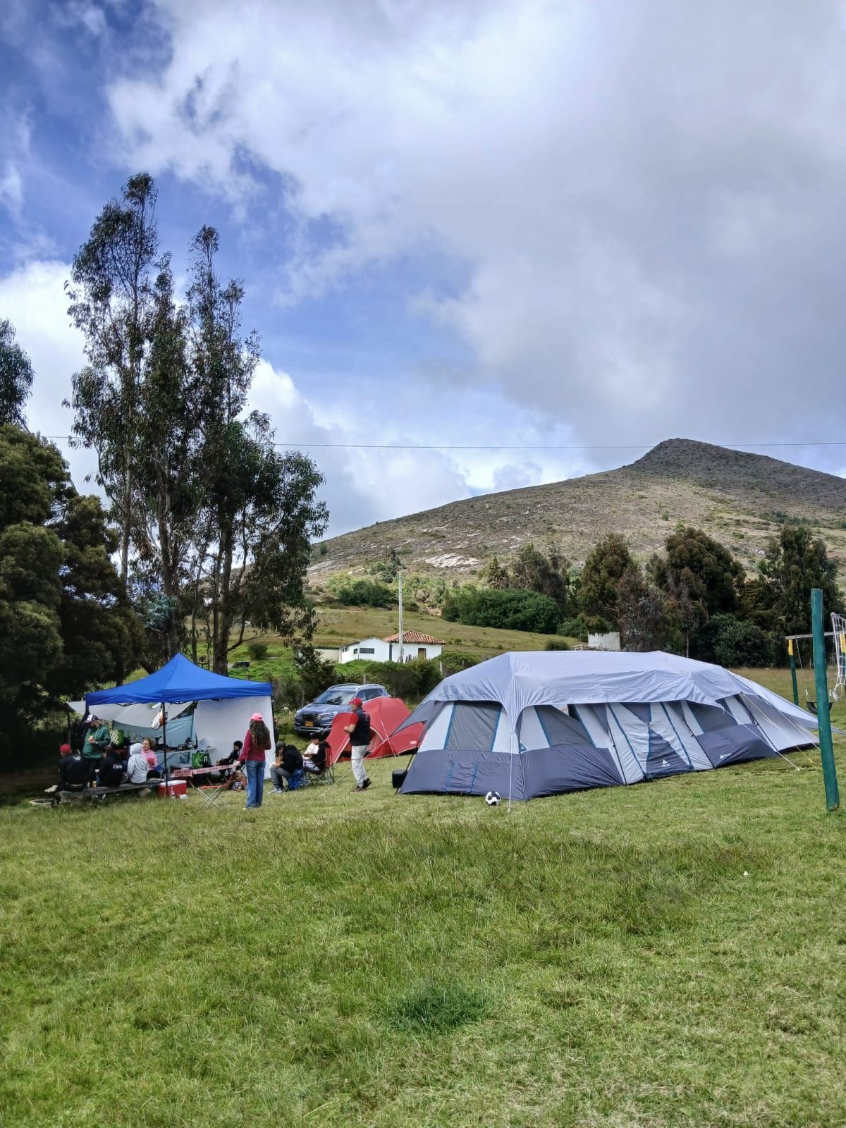 A grassy field with tents and a hill in the background.