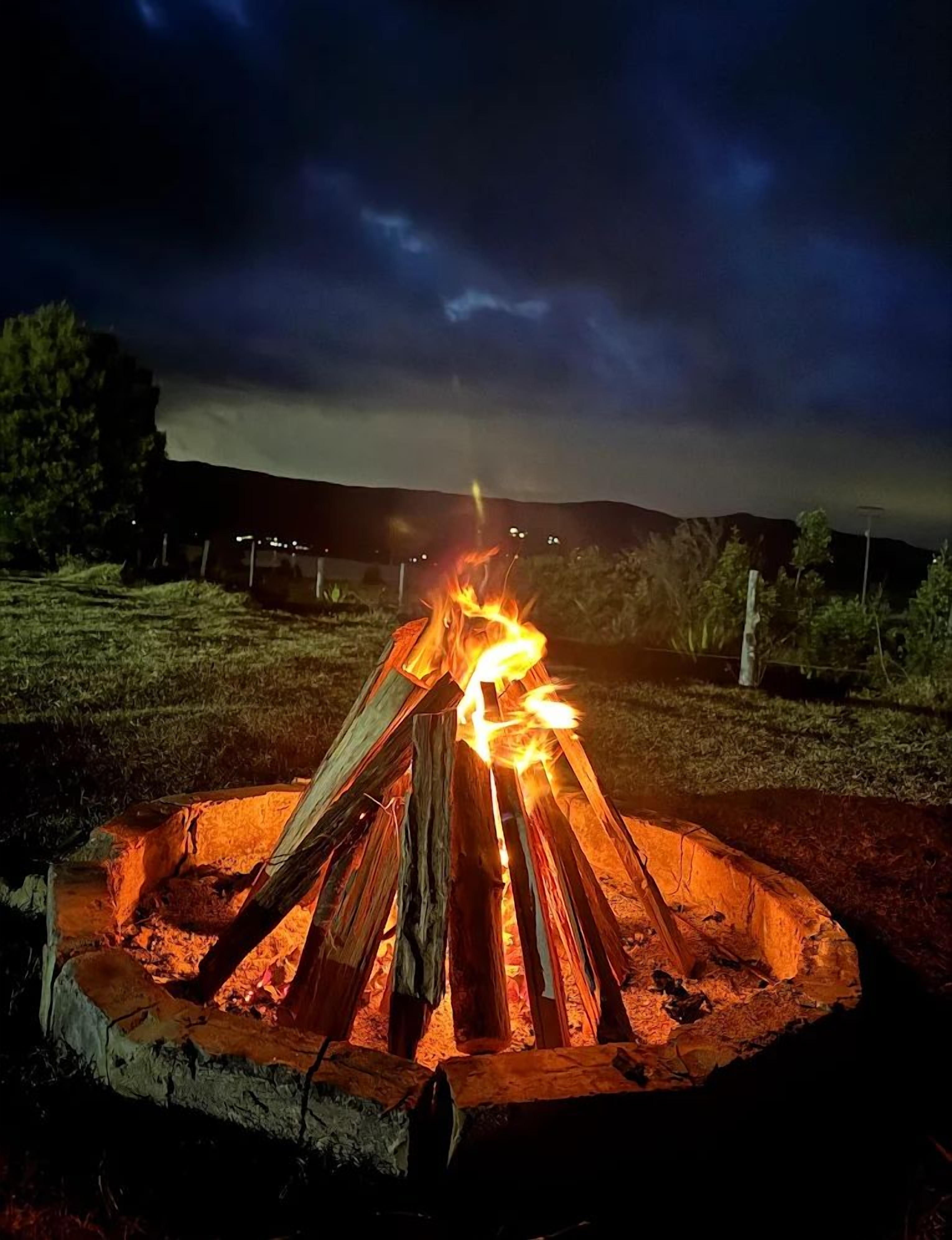 A campfire at night with a dark sky and distant hills.