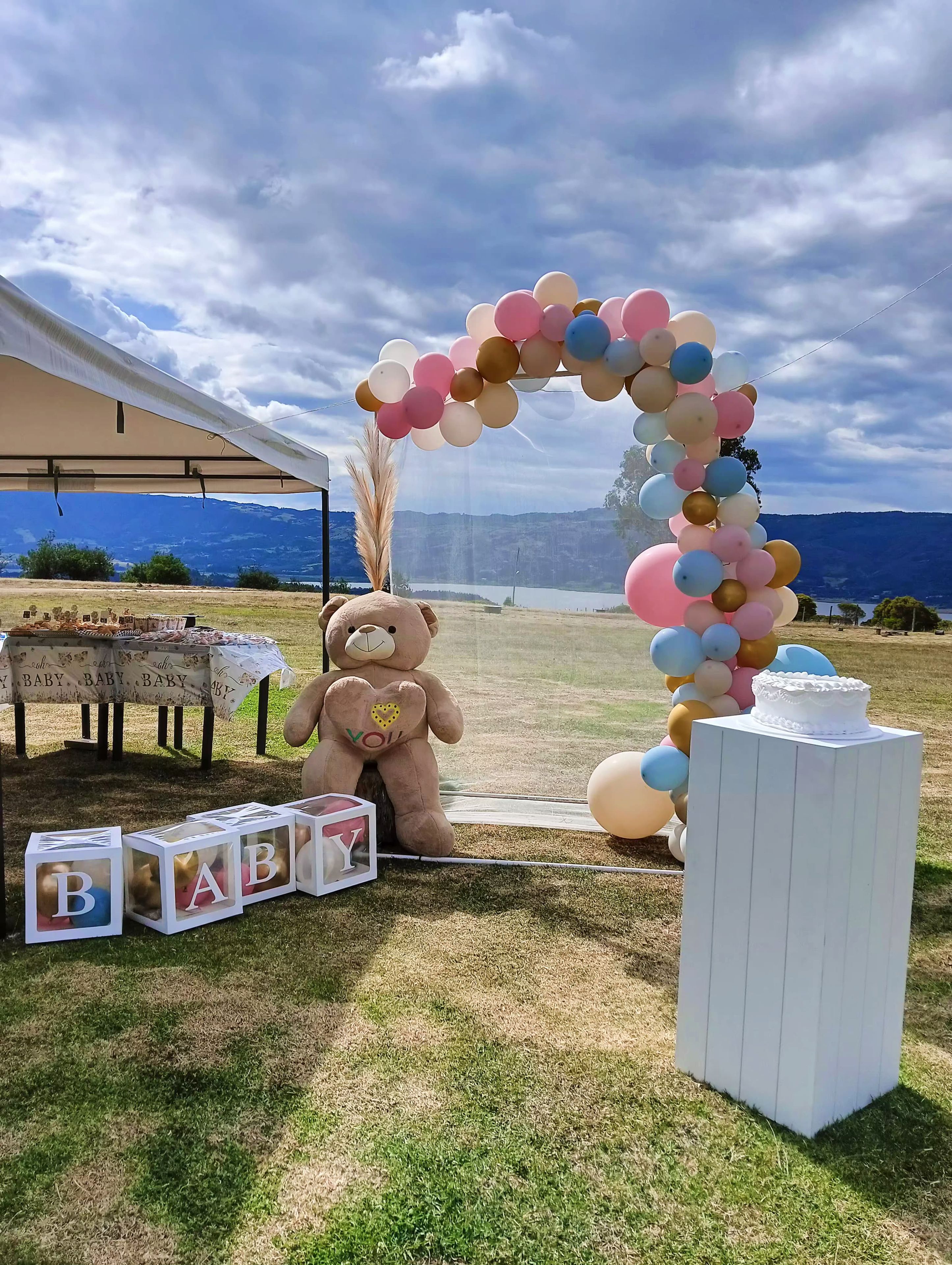 Decoración para una fiesta de bebé con un osito de peluche, globos y bloques para bebés.