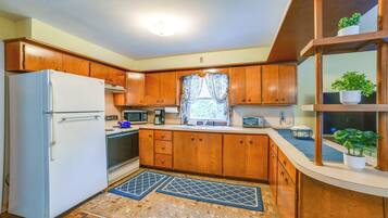 A compact kitchen with wooden cabinets, a white refrigerator, a microwave, and a sink.