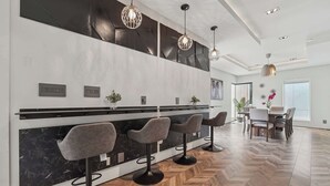 A modern kitchen with a marble countertop, bar stools, pendant lighting, and a dining area with a table and chairs. - Near Zoo Atlanta | Modern 4BR Home, Sleeps 8 (Atlanta)