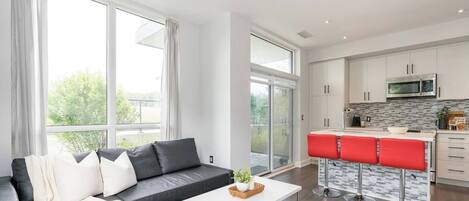 A modern apartment with a living room, kitchen, and a balcony.