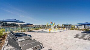 Un vaste espace extérieur doté d’une piscine, de coins salon et d’une aire de jeux.