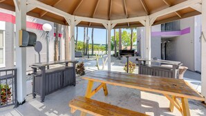 A covered outdoor seating area with a wooden table and benches, a grill, and a mailbox. - 2 Mi to Disney & Old Town: Resort Condo w/ Perks (Kissimmee)