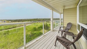 A covered outdoor area with a view of a grassy landscape and a road. There are two chairs and a table.
