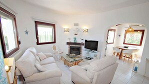 A living room with two white sofas, a glass coffee table, a fireplace, and a TV. - Azahar - villa with privat pool in Moraira (Moraira)