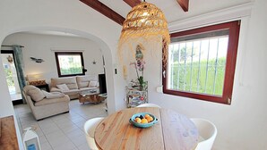 A living room with a round wooden table, a sofa, and a hanging light fixture. - Azahar - villa with privat pool in Moraira (Moraira)
