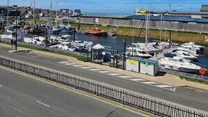 Un port de plaisance avec des bateaux amarrés, une jetée en bois et une route au premier plan.
