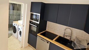 Une cuisine compacte équipée d’un lave-vaisselle, d’un four et d’un lave-linge.