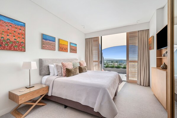 Une chambre d’hôtel moderne avec un grand lit, une table de chevet, une télévision et une vue sur la ville.
