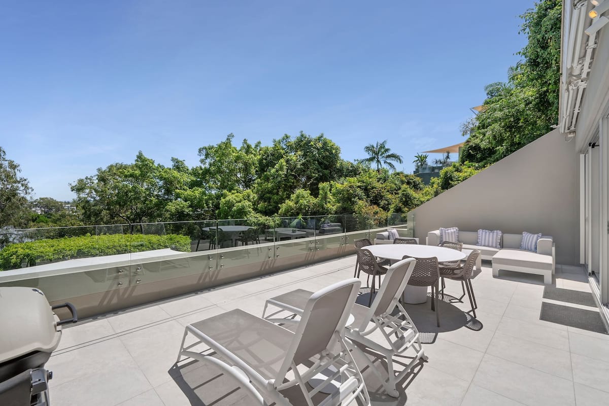 Une terrasse sur le toit, avec des sièges extérieurs, un barbecue et une vue sur la verdure et les bâtiments.