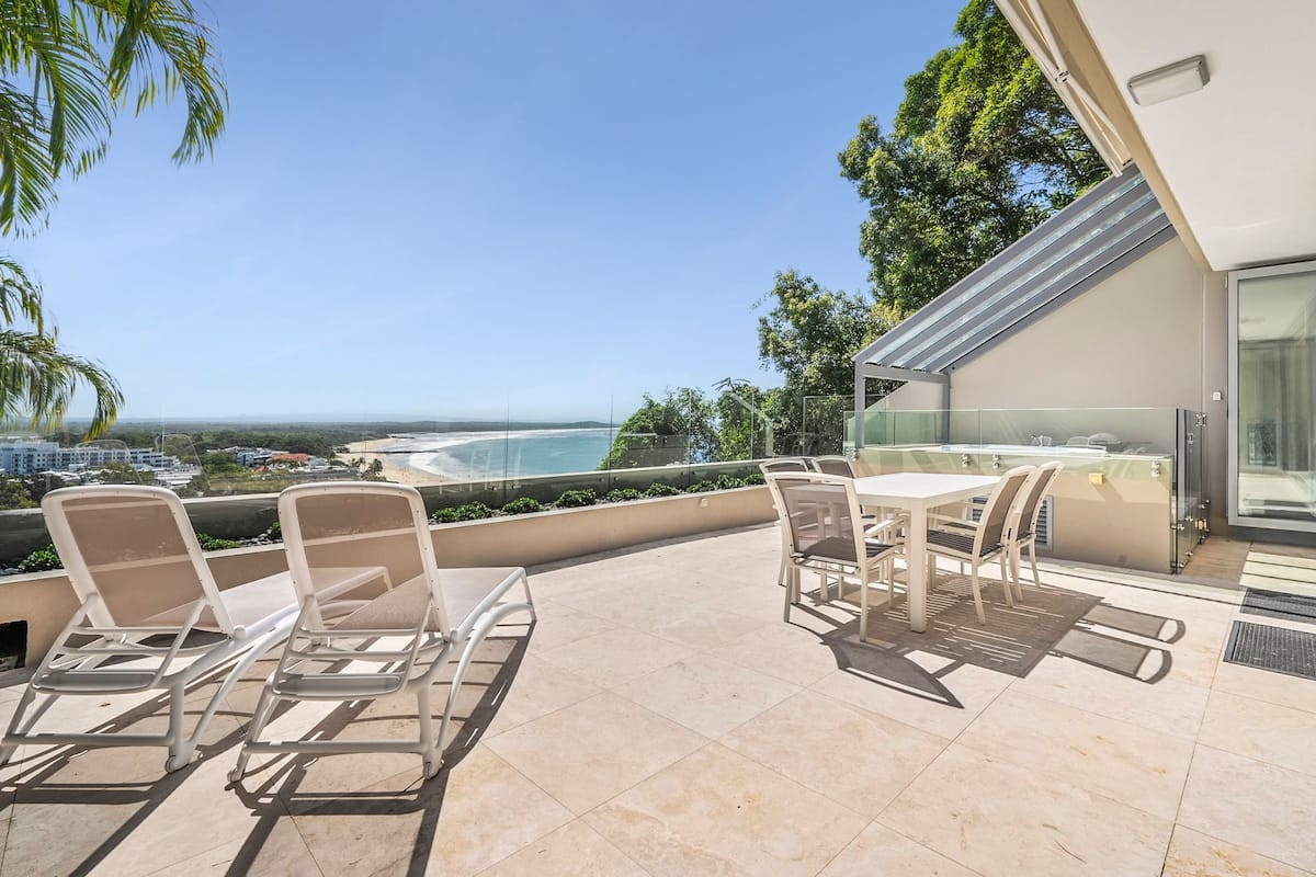 Une terrasse sur le toit dotée d’une balustrade en verre, d’un espace salon extérieur et offrant une vue sur l’océan.