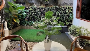 Une cour avec une petite piscine, du gazon synthétique et diverses plantes en pot.
