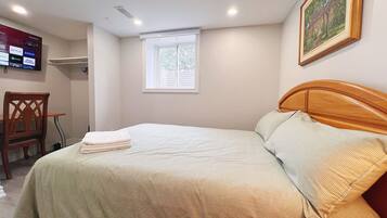 Una cama bien hecha con una colcha a rayas, un cabecero de madera y una ventana con persianas.