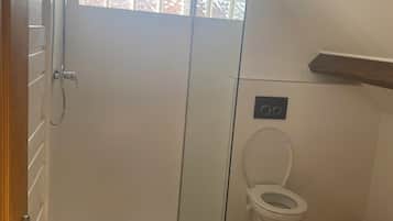 Een douche, handdoeken, zeep, toiletpapier