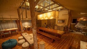 Un intérieur rustique en bois, avec une grande table à manger, des bancs et un luminaire suspendu.