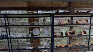 A rustic interior with woven furniture, wooden tables, and shelves displaying pottery. - JavaLO Lite (Pujut)