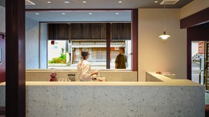 A restaurant interior with a counter, a person standing by the window, and a hanging light fixture. - Komado Bengara (Komatsu)