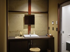 Un baño con tocador de madera, un espejo y un lavabo.