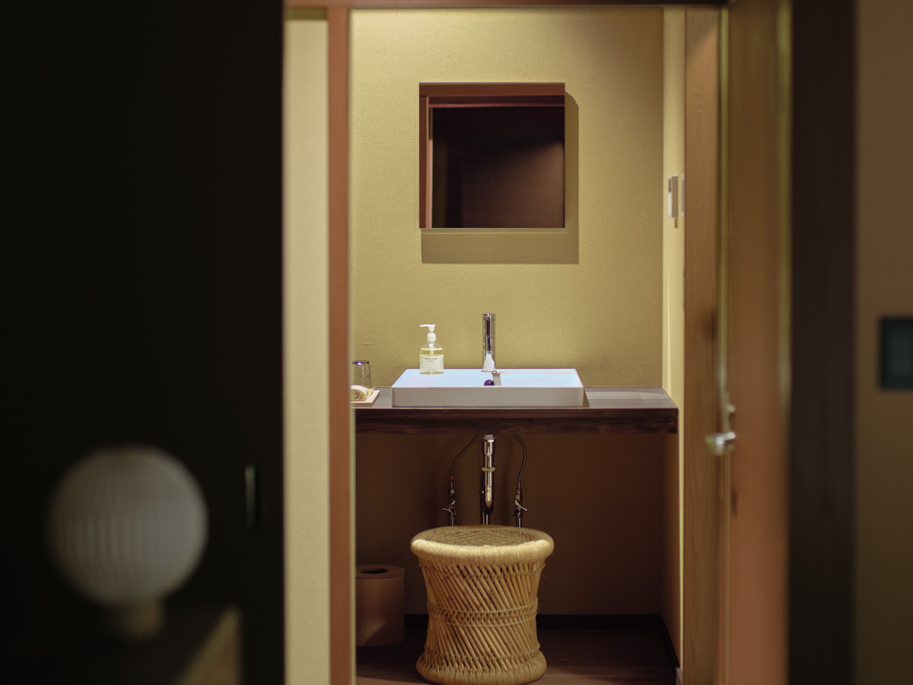 A compact bathroom with a sink, mirror, and a small wicker basket.
