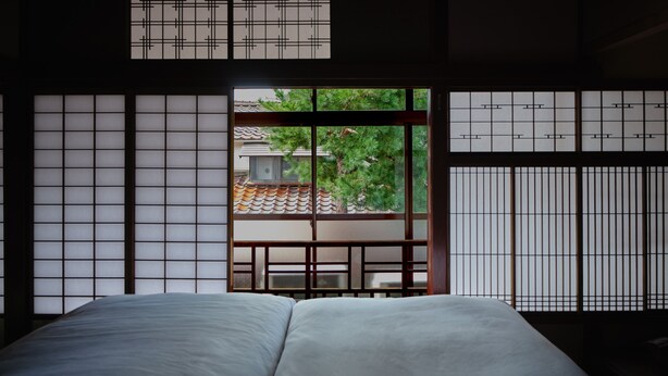 A traditional Japanese-style room with tatami flooring, a low wooden bed, and shoji screens. - Komado Bengara (Komatsu)